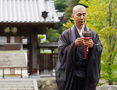 A Buddhist monk stands calmly in front of a temple, embodying the stillness of mindful Zen practice.